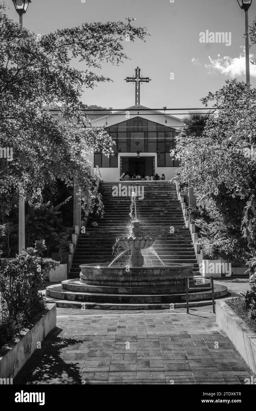 La tranquillità tropicale incontra la spiritualità moderna: Una pittoresca chiesa moderna abbellisce un piccolo villaggio messicano a Nayarit, circondato da una lussureggiante vegetazione tropicale Foto Stock