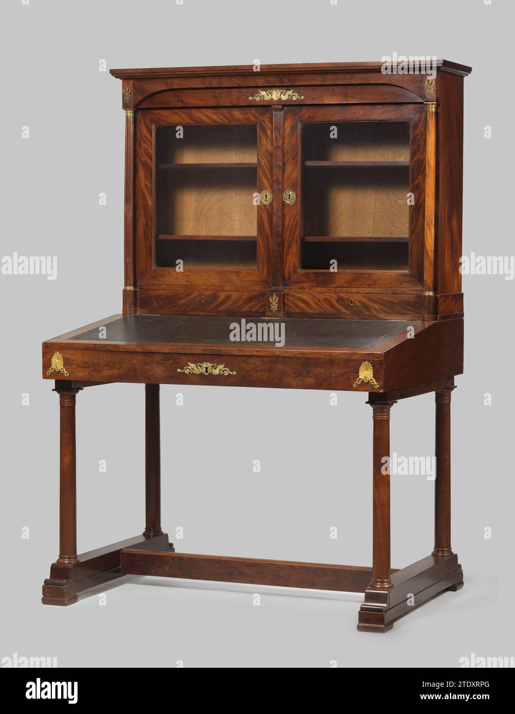 Bureautafel, anonimo, c. 1820 scrivania in quercia Lijmed con mogano, con pastella di rame dorato. Il foglio di scrittura inclinato è il coperchio di un vano portaoggetti, poggiato su quattro colonne toscane su piedini da slitta tra cui una traversa. La pre-regola porta la pastella sotto forma di palmeti e un piatto con cigni, tendini e scudo. Il montante è dotato di due sportelli con vetro e cassetti, posizionati tra le colonne su un seminterrato rotondo. Nel cofano sopra di esso ci sono case con pastella, tra cui una barra cieca con pastella come sulla linea pre-line. Legno (probabilmente) dei Paesi Bassi settentrionali (materiale vegetale). quercia (legno). mogano (legno). co Foto Stock