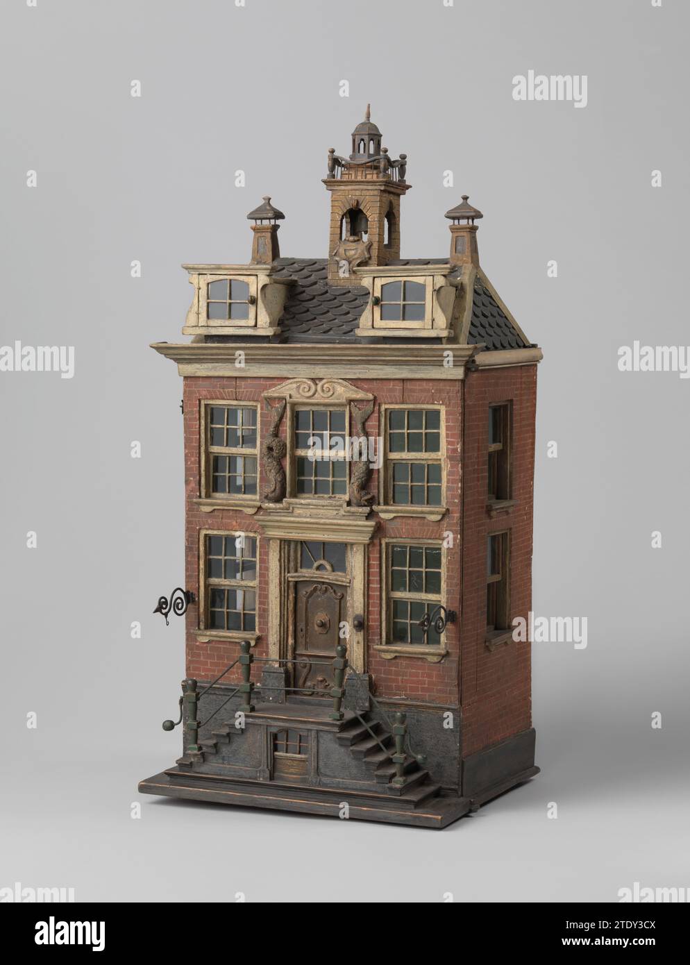 Modello, 1700 - 1800 modello di casa a due piani con marciapiede alto. Due finestre con piccoli diamanti su entrambi i lati della porta d'ingresso. Due delfini su entrambi i lati della finestra sopra la porta. Due finestre dormitori con finestre aperte sul tetto. Due camini con un tetto e una torre con un orologio al centro. Incernierato anteriore. Verniciato dall'interno di verde chiaro senza ulteriori ornamenti. La cerniera e i finestrini laterali sono applicati al testimone, come testimoniano le viti e i chiodi dei fili. (Sotto la finestra del seminterrato c'è il testo, restaurato nel 1963) legno (materiale vegetale). Modello in vetro di due -st Foto Stock
