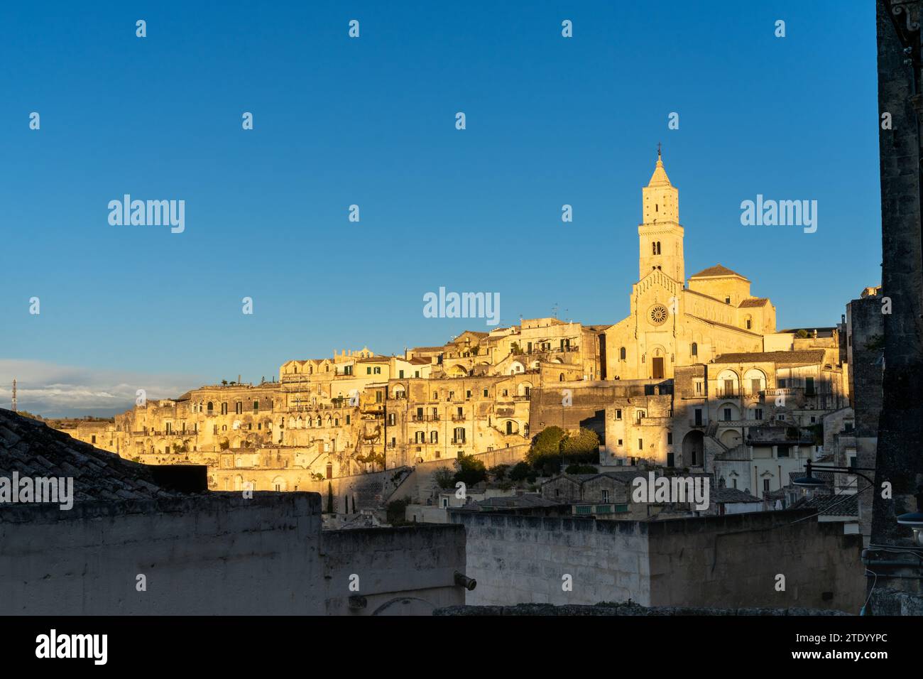 Matera, Italia - 26 novembre 2023: Vista della storica Cattedrale di Maratea e delle case in pietra dei Sassi di Matera nella calda luce dorata della sera Foto Stock
