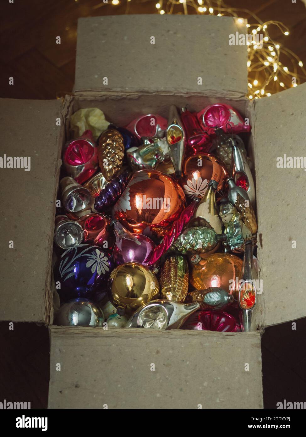Immagine verticale direttamente dall'alto di una vecchia scatola aperta con decorazioni vintage sull'albero di Natale e luci elettriche moderne. Magia del tempo dell'avvento Foto Stock