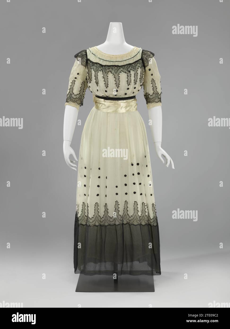 Abito a tre strati di georgette crepe, Anonimo, c. 1916 - c. 1919 l'abito è composto da tre strati incrociati di georgette crepe; Un abito inferiore bianco, un abito "eau de nil" e un abito bianco con abito nero. Questo ha dato al tutto un bagliore blu-verde. Sorprendentemente contemporanei sono i cerchi dello pneumatico arrotolato in raso nero sulla gonna bianca e i fronzoli annodati in bianco e nero sulla cintura. La gonna è libera dai piedi e abbastanza spaziosa per una libertà di movimento sufficiente. Paesi Bassi (possibilmente)Francia (possibilmente) intero: Silk. lato:. Ceintuur: Pizzo con nastro di seta/pizzo con nastro di seta Foto Stock
