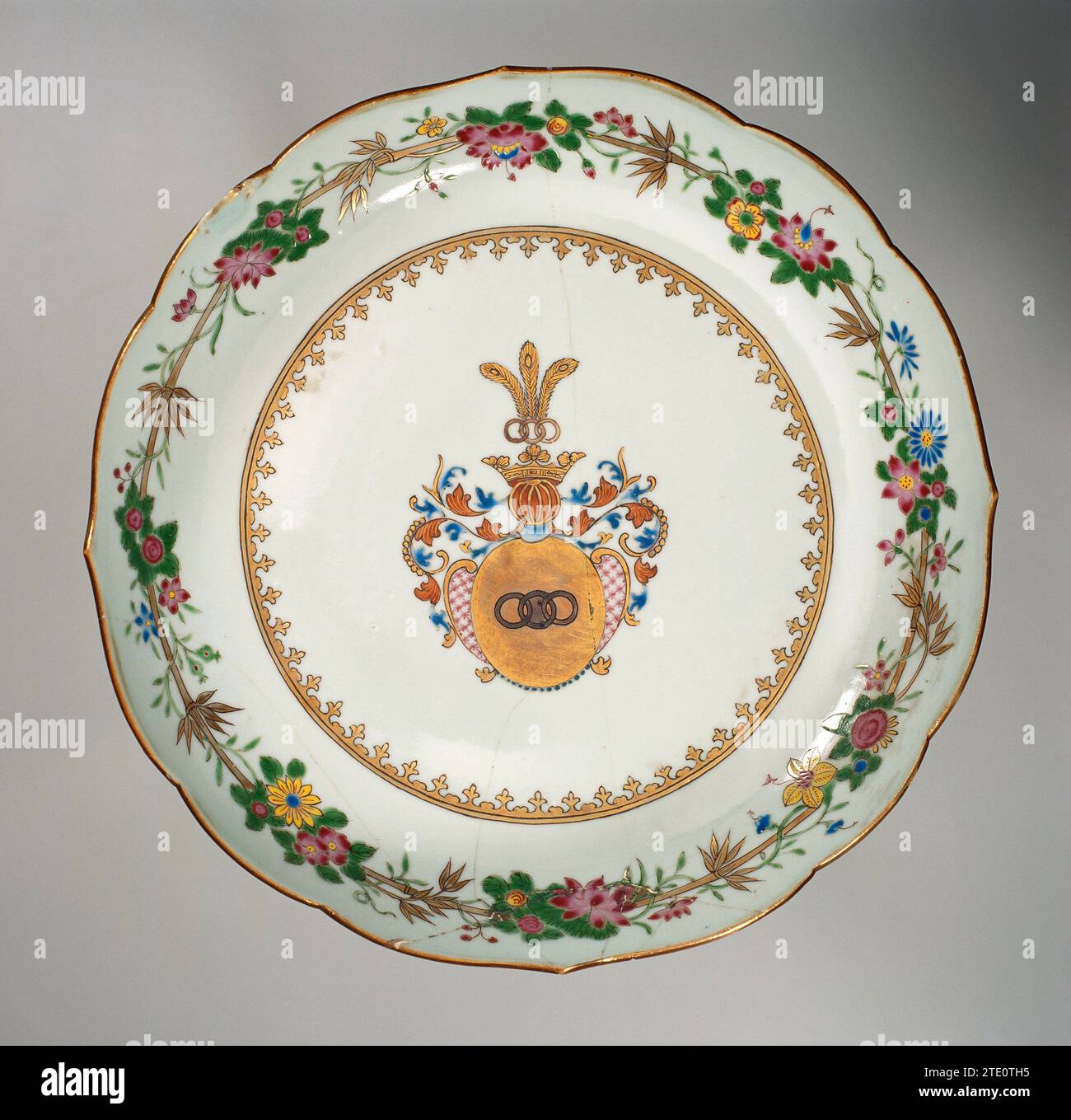 Piatto di salame con le braccia della famiglia Zurmegede, anonimo, c. 1755 - c. 1760 ciotola di porcellana con bordo smerlato, verniciata sulla glassa in blu, rosso, rosa, verde, giallo, nero e oro. Sul piatto lo stemma della famiglia Zurmegede in oro con tre anelli collegati. Il simbolo dell'elmetto è una corona con tre anelli collegati e molle in pavone sopra di essa. La copertina comprende un cartiglio con un motivo a diamante nello stile di Luigi XIV insieme a foglie e una fila di perle su entrambi i lati. Una punta di lancia sul muro. Sul bordo c'è una decorazione di viti floreali e di bambù. Piastra ha Foto Stock