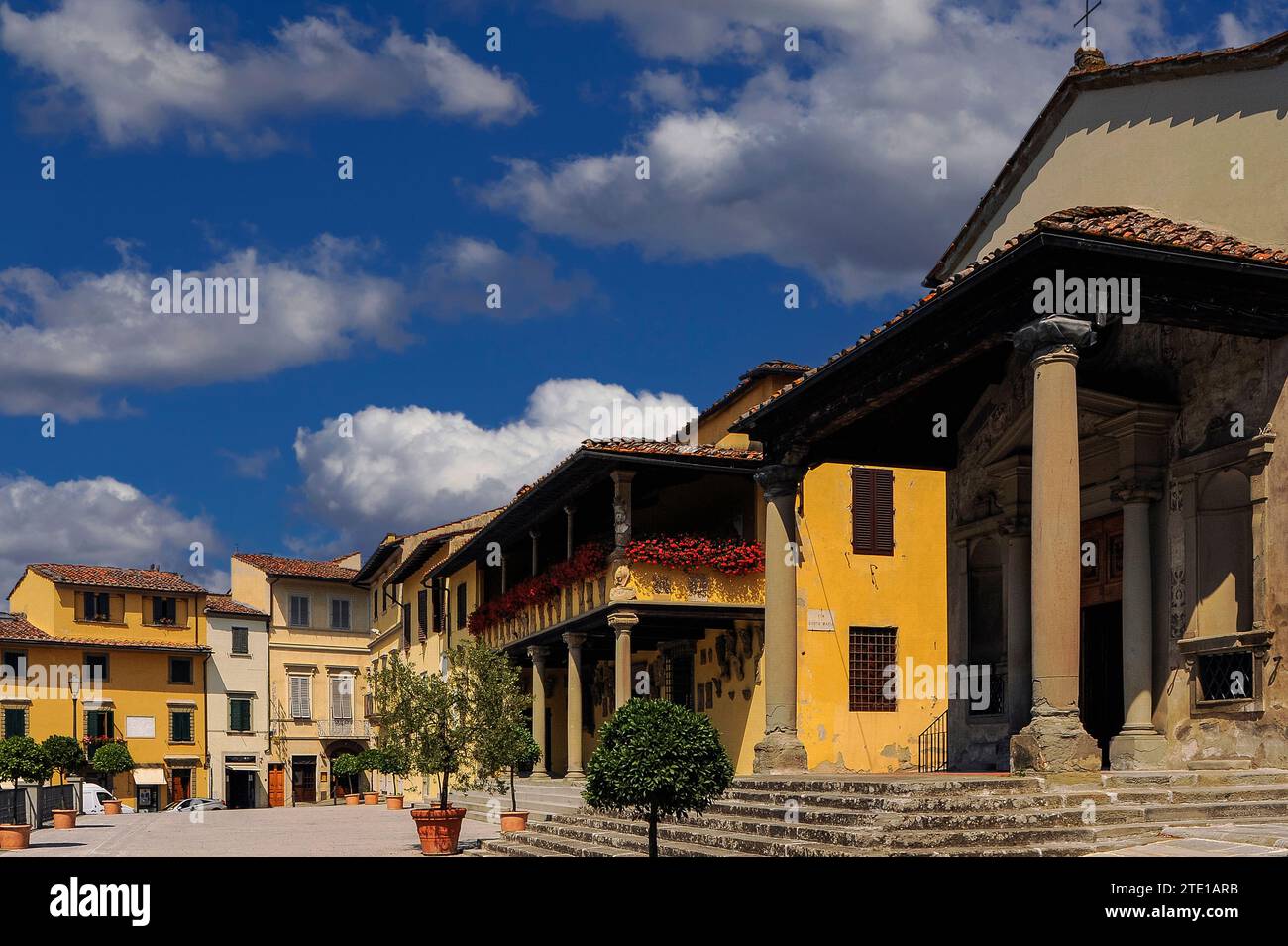 Fiori rossi brillanti decorano la loggia di Palazzo Pretorio o Municipio, affacciata sulla piazza principale di Fiesole, una cittadina collinare sopra Firenze, Toscana, Italia. A destra del Palazzo si trova il portico ionico della Chiesa di Santa Maria Primerana, che fu aggiunto a questa chiesa medievale nel 1801. La facciata della chiesa risale alla fine degli anni '1500 Via Santa Maria si trova tra il Palazzo e la chiesa. Foto Stock