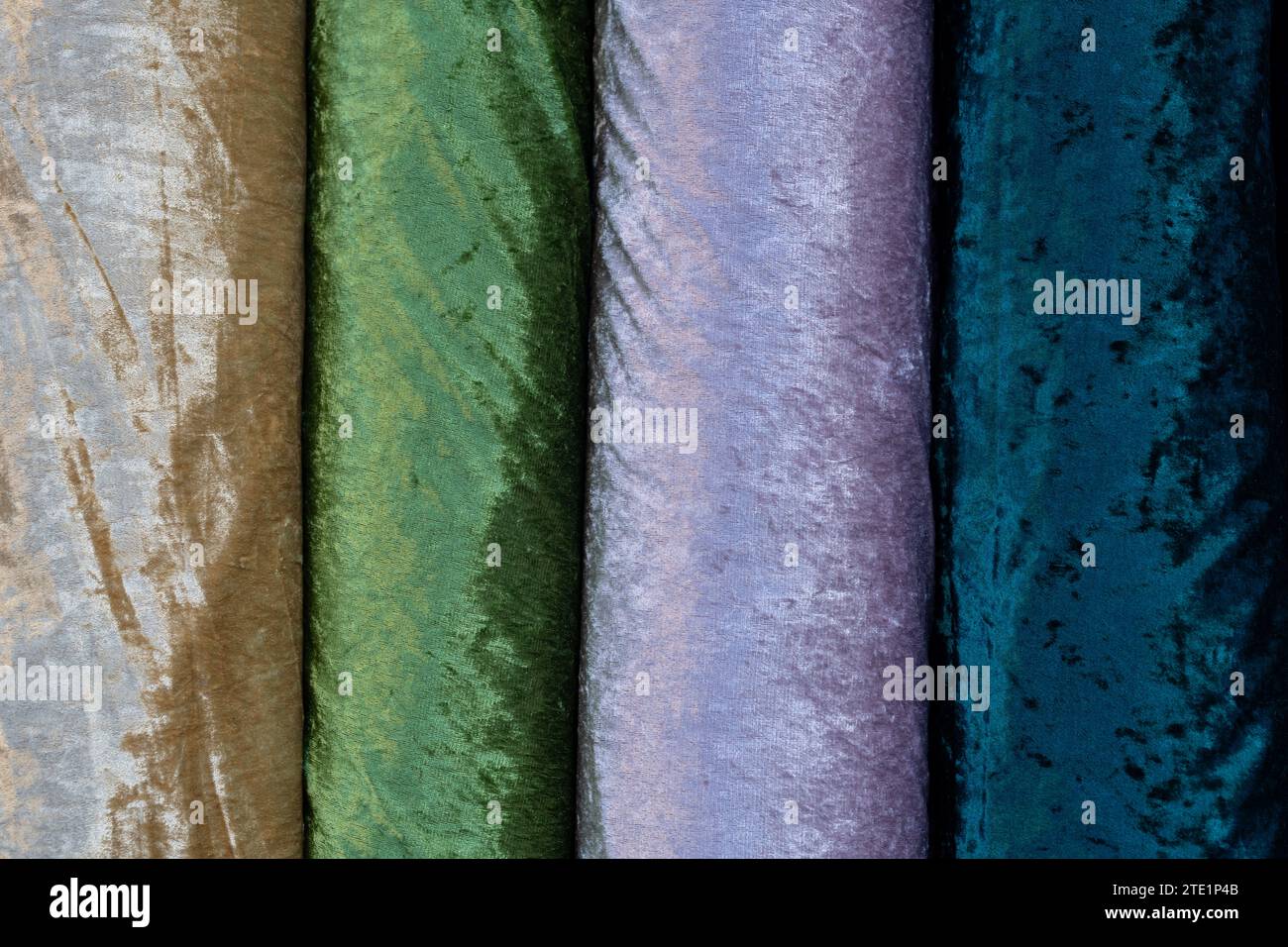 Dettaglio astratto di enormi bobine di tessuti in feltro dorato, verde, viola, lavendar e blu. Foto Stock