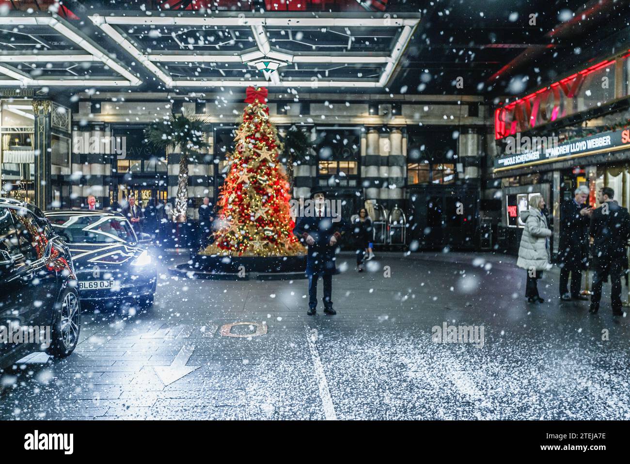 La neve finta cade fuori dall'ingresso del Savoy Hotel a Londra. Foto Stock