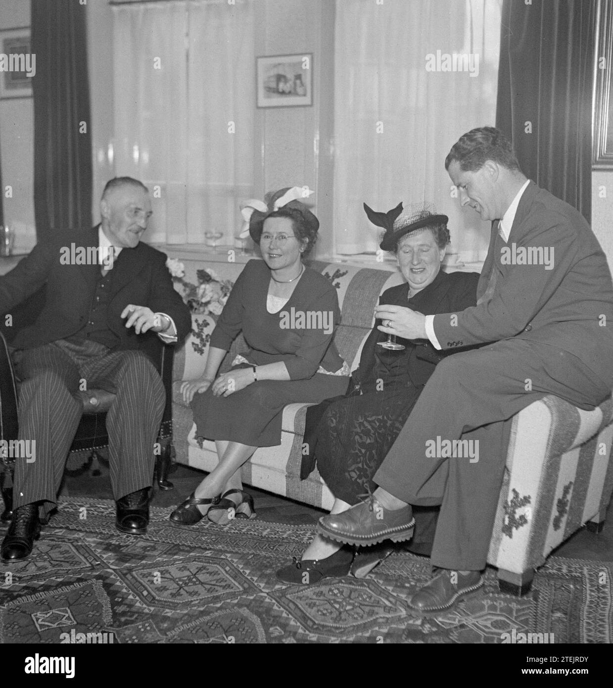 Due uomini che parlano con due donne su un divano CA. 1950 Foto Stock