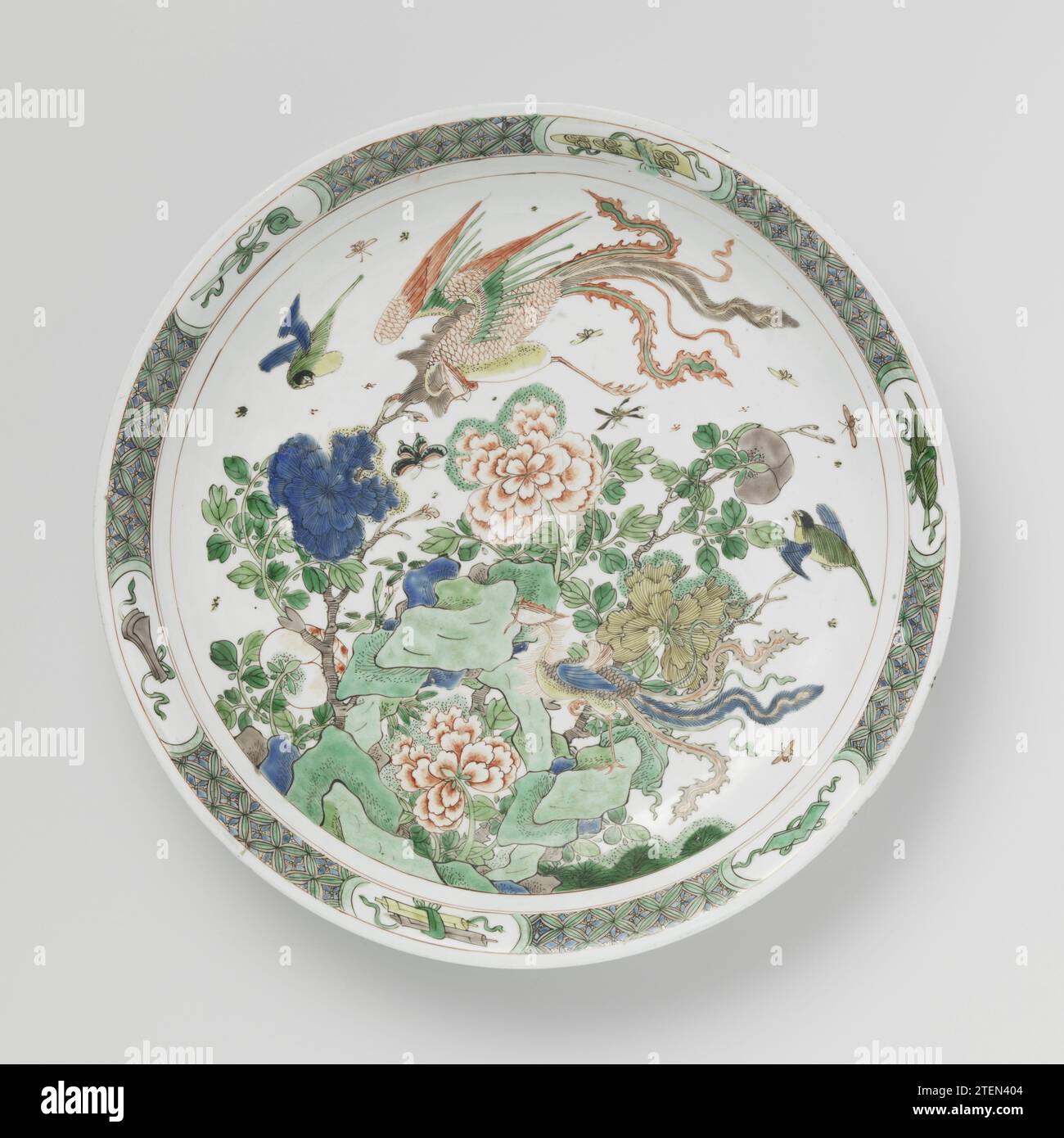 Piatto-piatto con rocce, fiori e huangs feng, anonimo, c. 1700 - c. 1724 piatto con parete rotonda, spalmabile di porcellana, verniciato in blu sotto smalto e sopra lo smalto blu, rosso, verde, giallo, melanzana e nero. Sulle rocce piatte con rami di torbiere fioriti e due Feng Huang, altri uccelli e insetti; il bordo con motivo geometrico intervallato da simboli fortunati (calamite, scettro, rotoli di libri, pietra musicale, artemisia magazine) nei cartigli. Il fondo con tre rami di fiori. Contrassegnato con un marchio di sigillo a doppio cerchio. Quattro chip sul bordo. Famle verte. Porcellana cinese. g Foto Stock