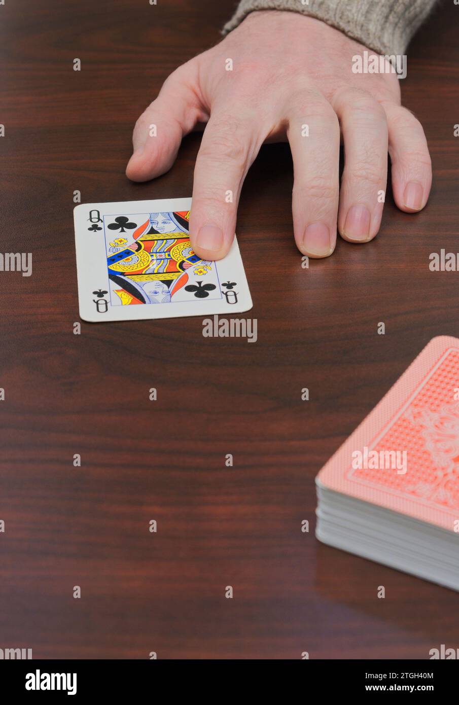 Mano sulla carta Regina di Fiori e mazzo di carte da gioco su tavolo di legno Foto Stock