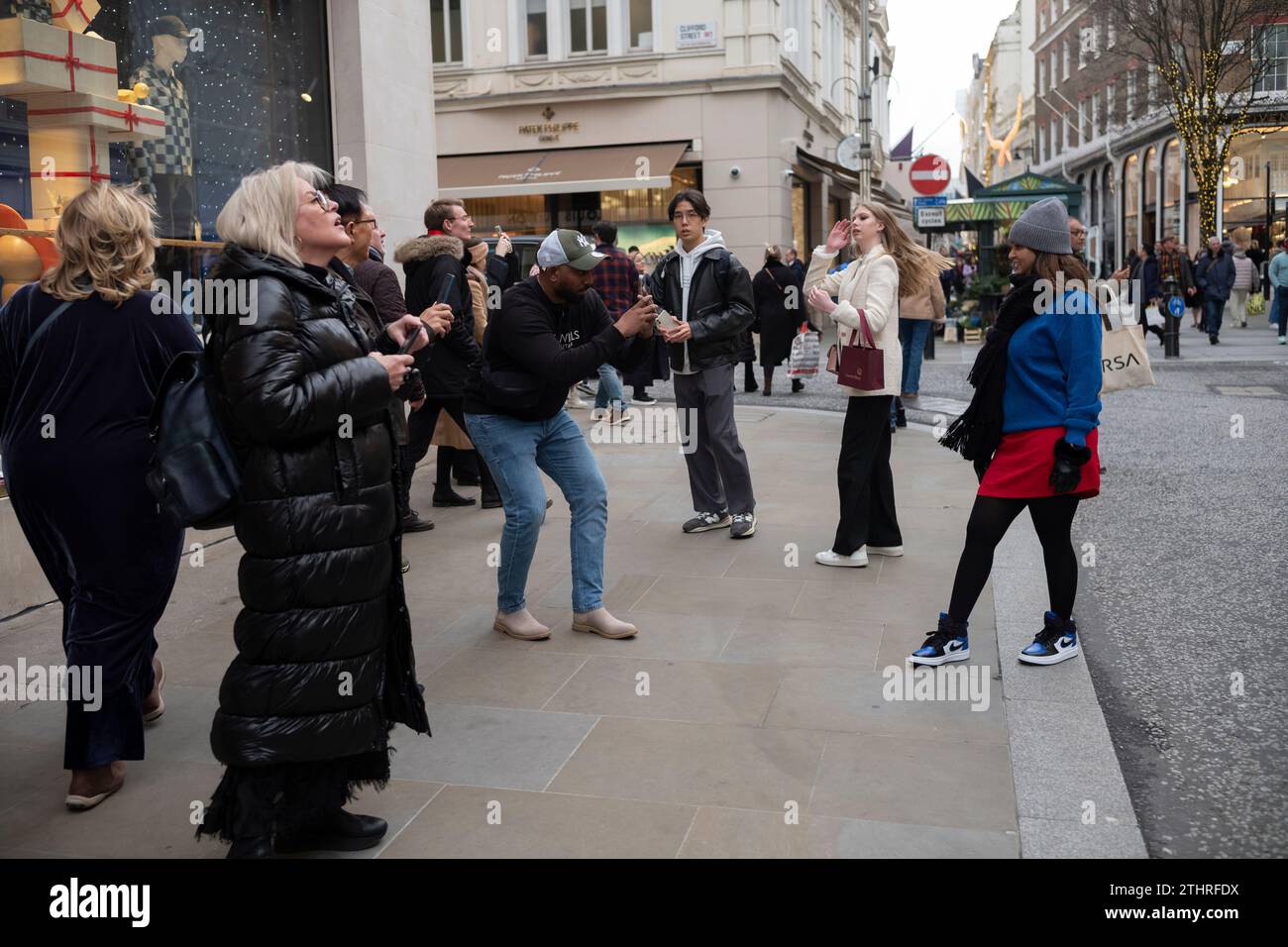 I turisti festivi in giro per la città scattano selfie e foto delle esposizioni di Natale lungo Old Bond Street, nel cuore della Mayfair di Londra, 20 dicembre 2023. Foto Stock