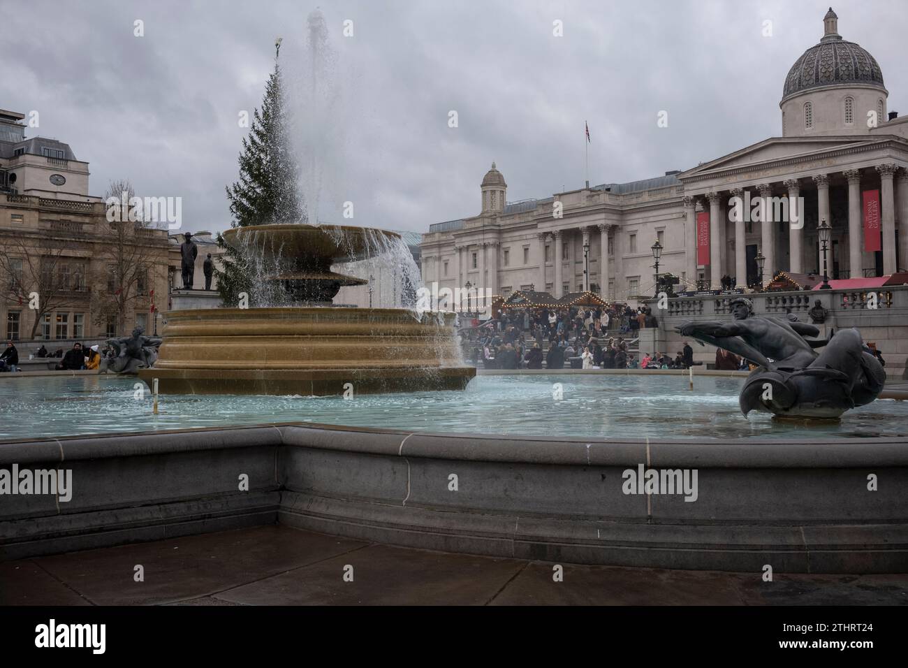 I turisti festivi si fanno dei selfie e delle foto l'uno dell'altro di fronte alle fontane di Trafalgar Square nel West End di Londra, 20 dicembre 2023 Foto Stock