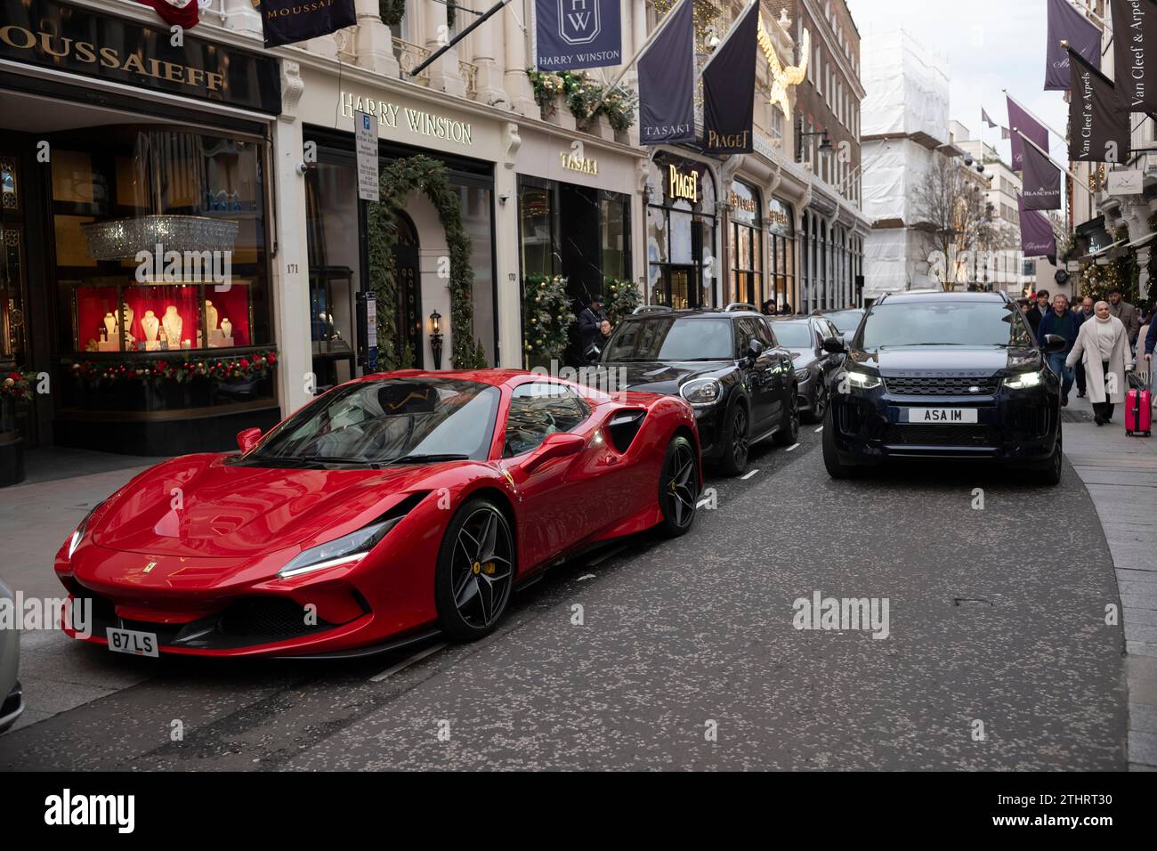 Super auto, tra cui una Ferrari rossa lungo Old Bond Street, nel cuore della Mayfair di Londra, prima di Natale 2023. Foto Stock