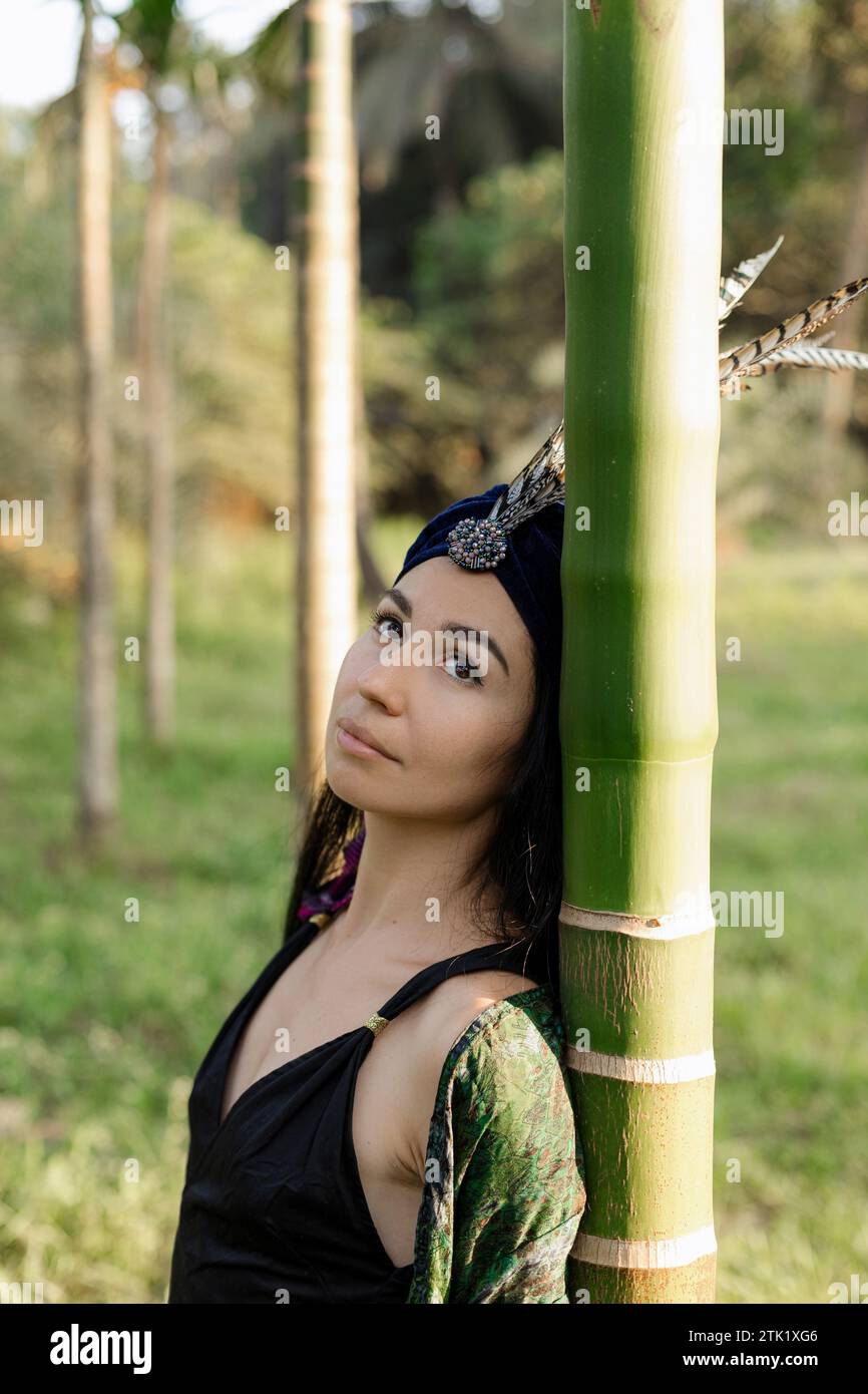 Primo piano del volto di una graziosa giovane donna dagli occhi marroni in abito nero a spalle scoperte. Foto Stock