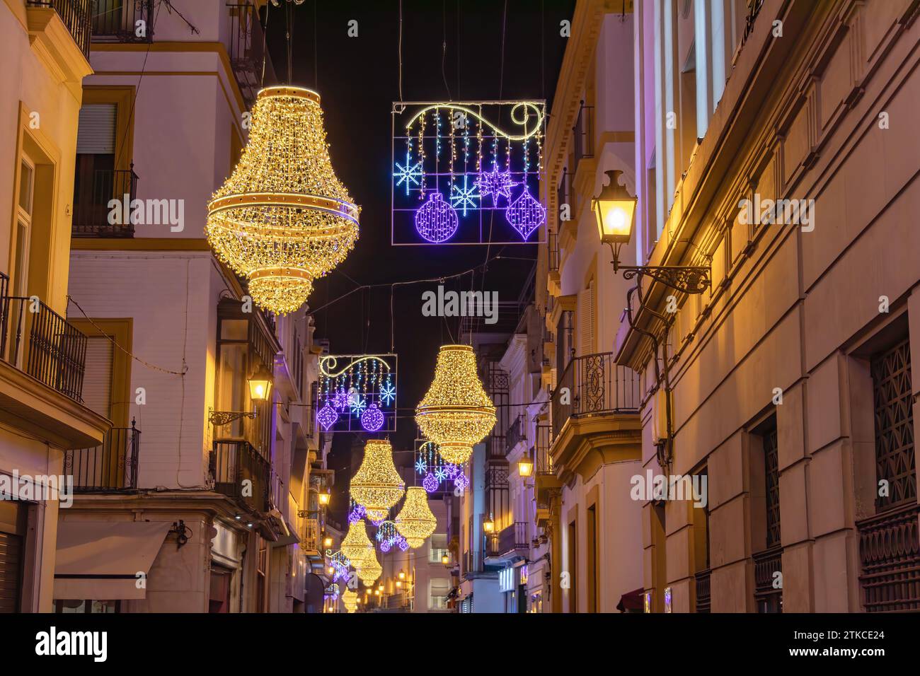 Decorazioni di luci natalizie in via Sierpes a forma di candelabro in cristallo in stile impero dorato, nel centro della città di Siviglia, Andalusia, Spai Foto Stock