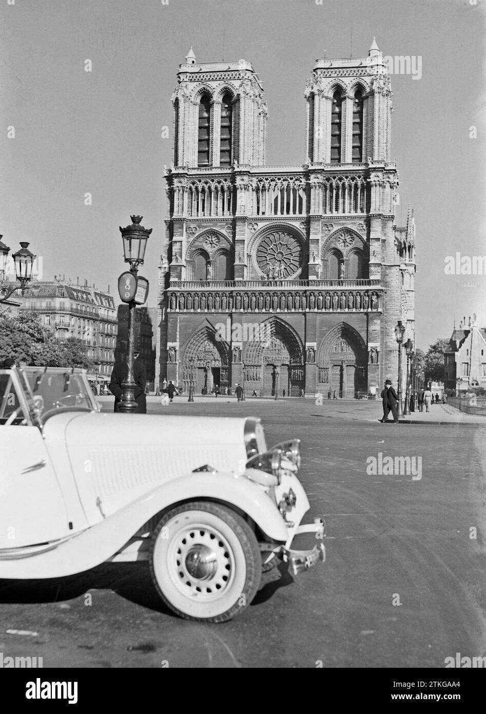 Parigi. Facciata ovest della cattedrale di Notre Dame con un'auto passeggeri e lampioni in primo piano, CA. 1937 Foto Stock