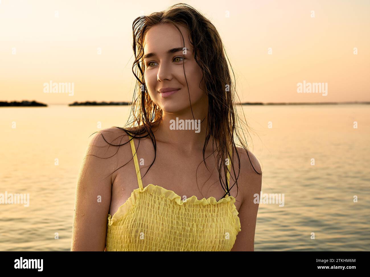 Ritratto ravvicinato di una giovane donna con un vestito giallo all'alba sullo sfondo del mare. La donna cammina in riva al mare Foto Stock