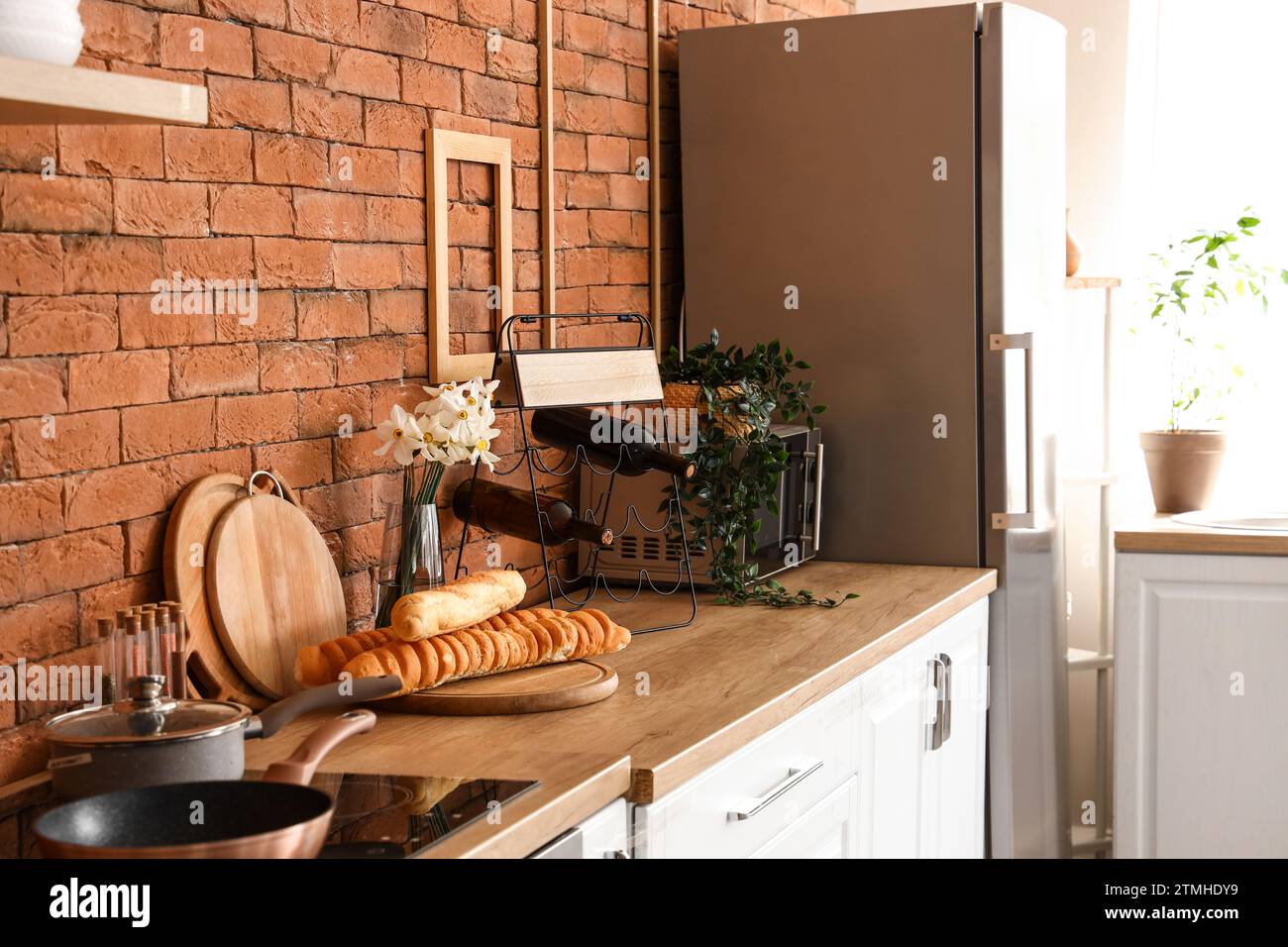 Interno della cucina con elegante frigorifero, ripiani, forno a microonde e pasticceria Foto Stock