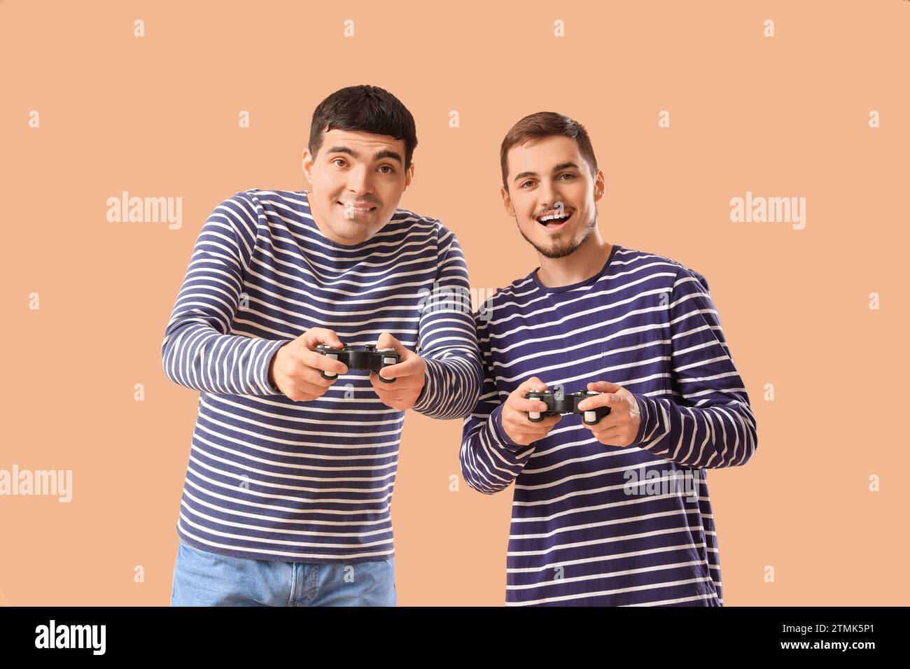 Giovani fratelli che giocano ai videogame su sfondo beige Foto Stock