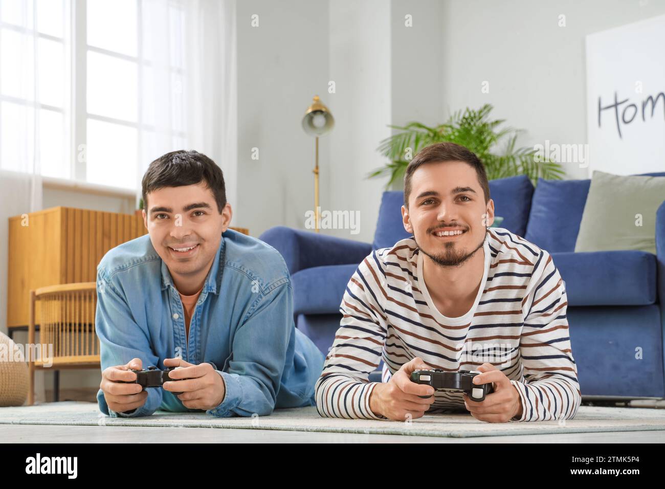 Giovani fratelli che giocano ai videogiochi in salotto Foto Stock