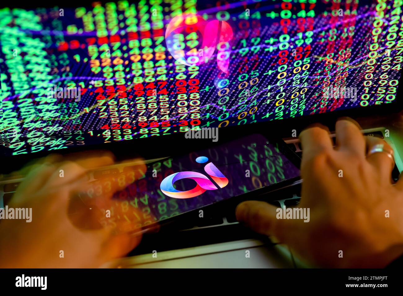 Cracovia, Polonia, 20 dicembre 2023. Questa foto mostra un logo dell'app Adobe ai visualizzato su uno smartphone e mani umane che lavorano su un computer con i numeri del mercato azionario sullo sfondo. Foto Stock