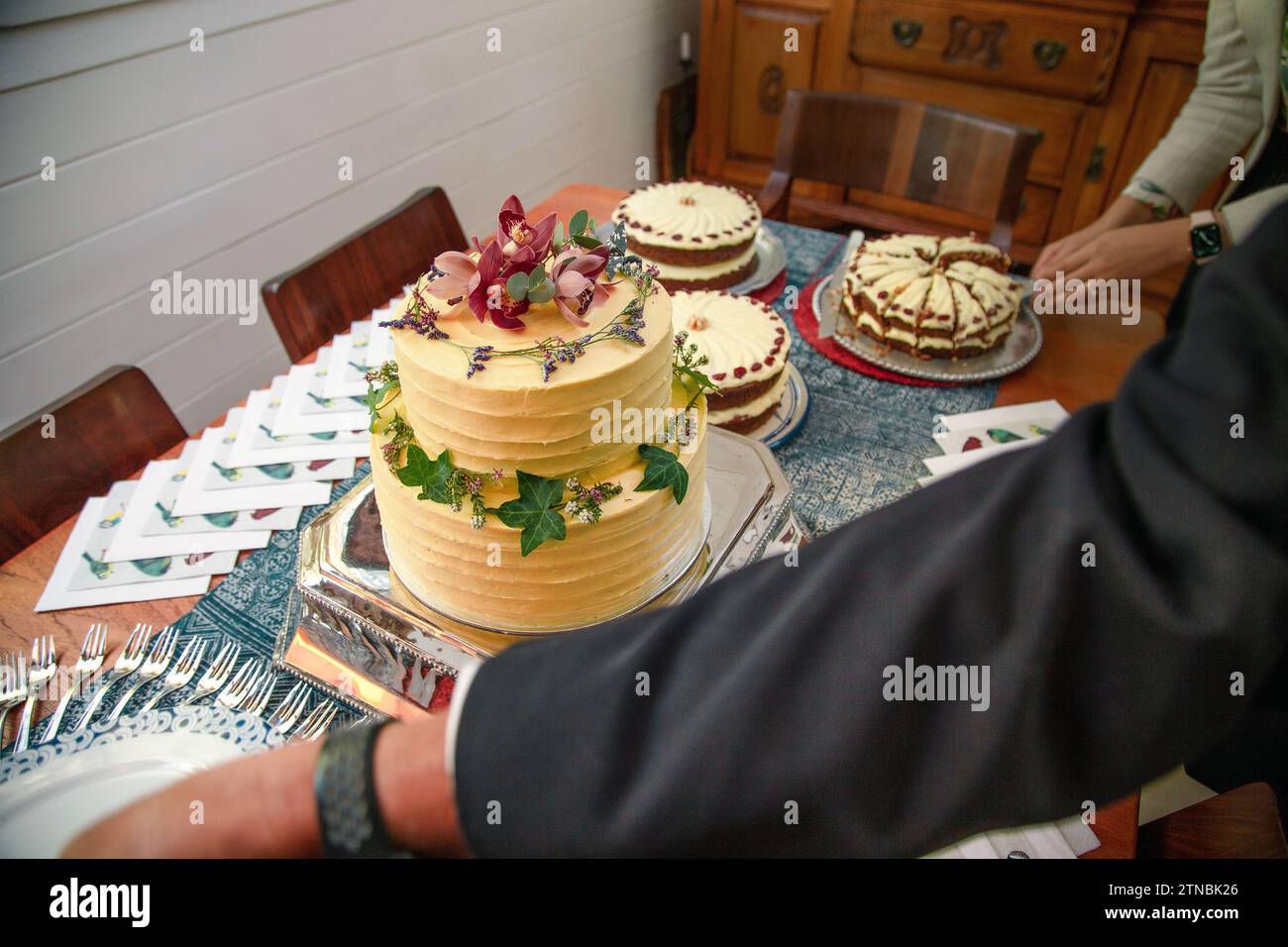 Un uomo che cerca piatti vicino a un tavolo di legno di bellissime torte bohémien a un matrimonio Foto Stock