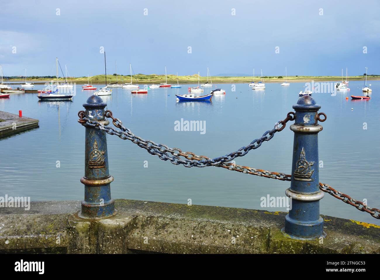 Pali d'ormeggio in ferro d'epoca incorniciano la vista delle barche a vela colorate all'ancora nella baia protetta di Malahide Marina in una luminosa giornata estiva ricoperta. Foto Stock