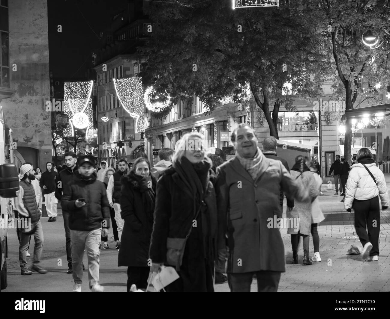 Un'accattivante fotografia in bianco e nero che cattura individui concentrati e sfocati nell'incantevole mercatino di Natale di Strasburgo Foto Stock