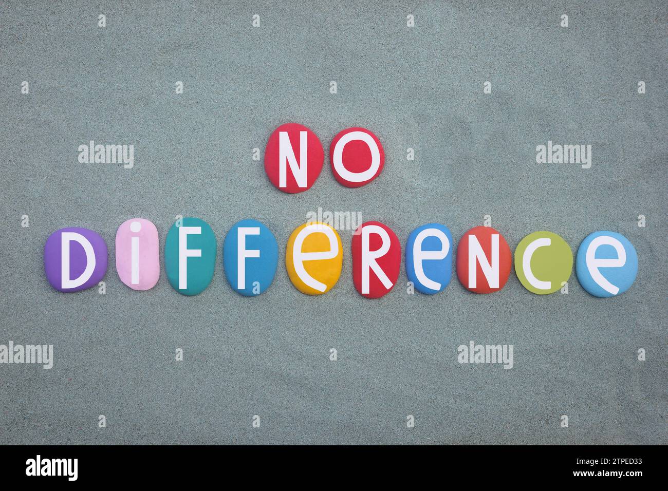 Non c'è differenza, slogan sociale composto da lettere di pietra multicolore dipinte a mano su sabbia verde Foto Stock