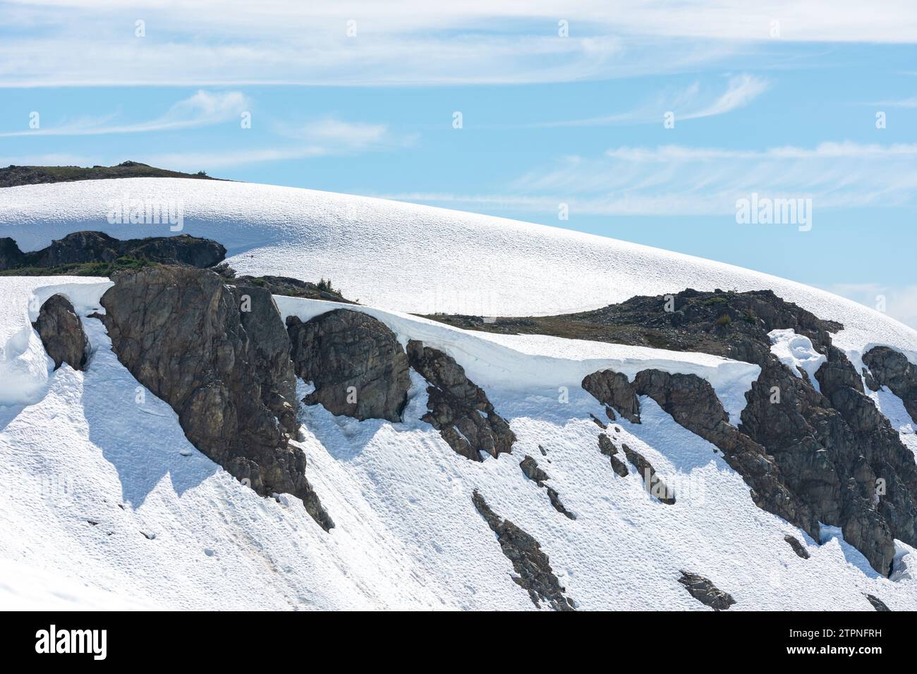 Il contrasto di neve e pietra forma la cresta contro un cielo limpido Foto Stock