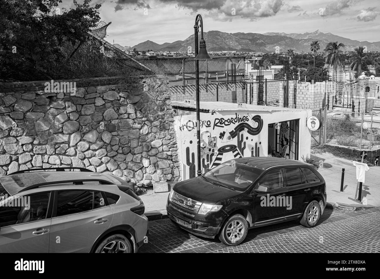 Foto di strada in bianco e nero del negozio di dischi Quiero Recordings e vista della grande San Jose del Cabo. Foto Stock