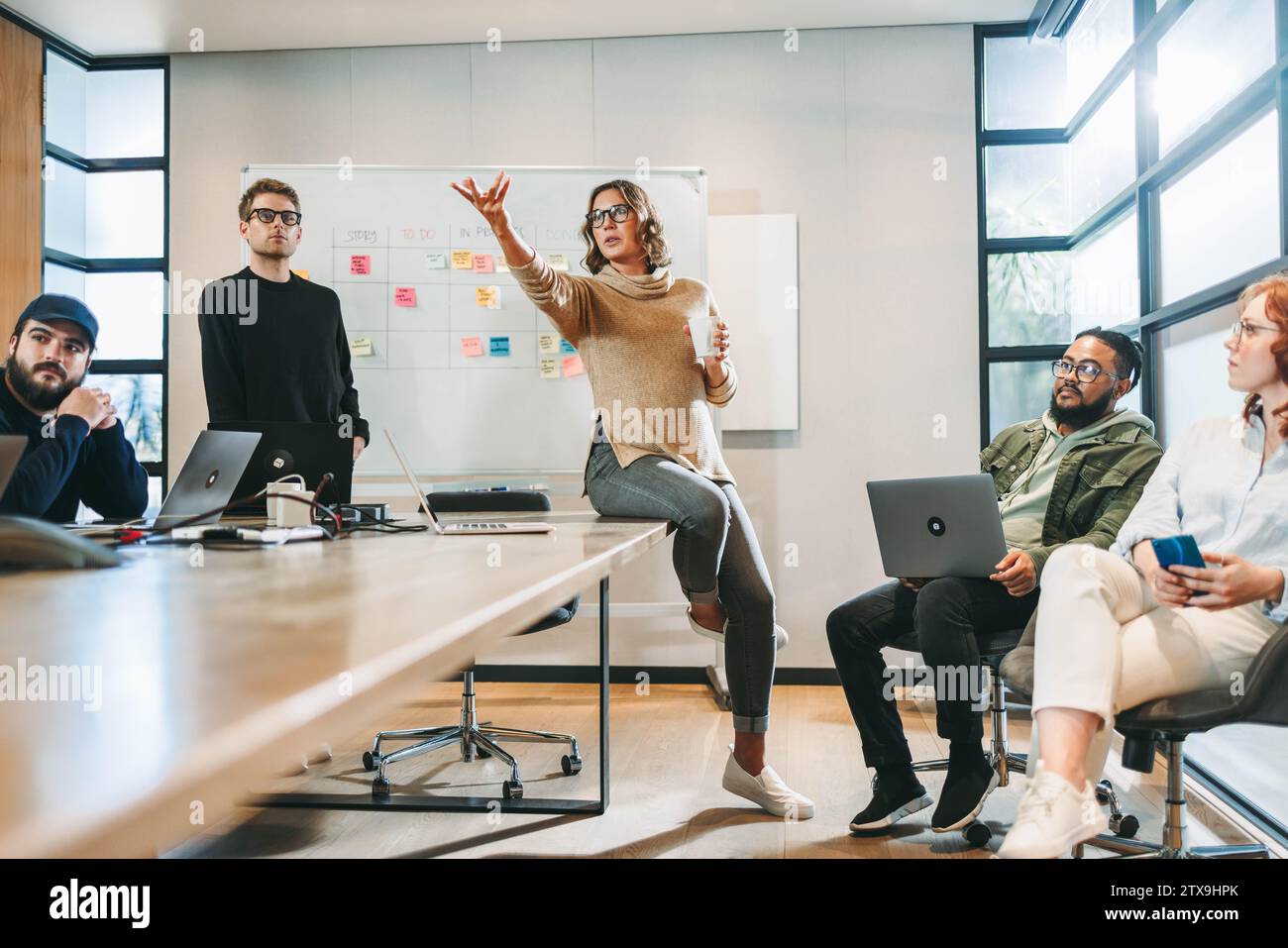 gli uomini d'affari si impegnano in una discussione vivace, mostrando un lavoro di squadra collaborativo. Guidati da un leader carismatico, hanno brainstorming idee creative per una so Foto Stock