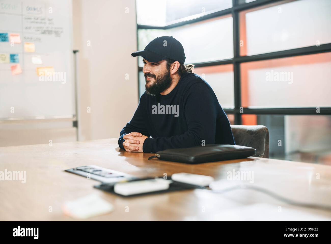 Il giovane imprenditore si impegna in una discussione creativa con il suo team professionale in una sala riunioni di ufficio. Questo felice e sorridente uomo d'affari mostra la sua Foto Stock