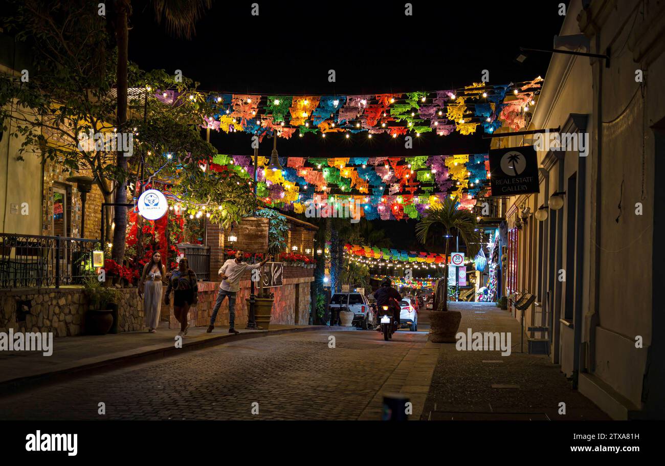 Un uomo onda di notte in una delle colorate strade acciottolate decorate con i picados di papel (bandiere colorate) nell'area del centro storico. Foto Stock