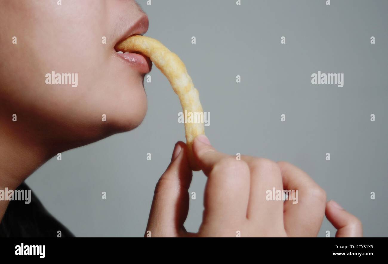 Donna che mangia pasticcini croccanti, è un popolare cibo di strada che è delizioso e si trova comunemente in paesi asiatici come Thailandia, Cina, Laos, Vietn Foto Stock