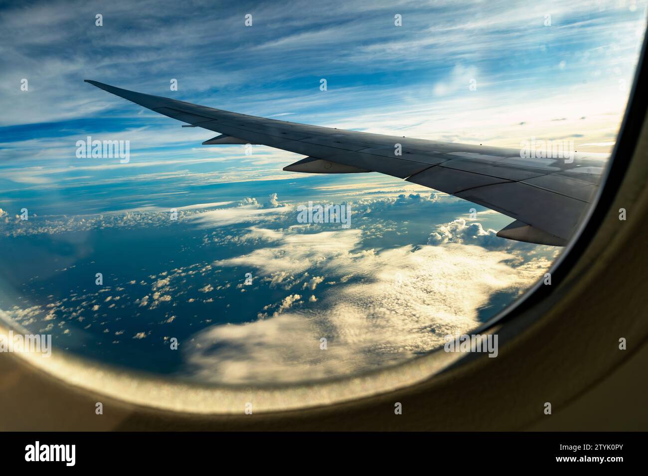 Ala dell'aereo, cielo blu con molte nuvole, mare sotto, vista aerea dalla finestra dell'aereo. Al mattino presto, alba sopra l'oceano Indiano. Altitudine 12000 m. Foto Stock