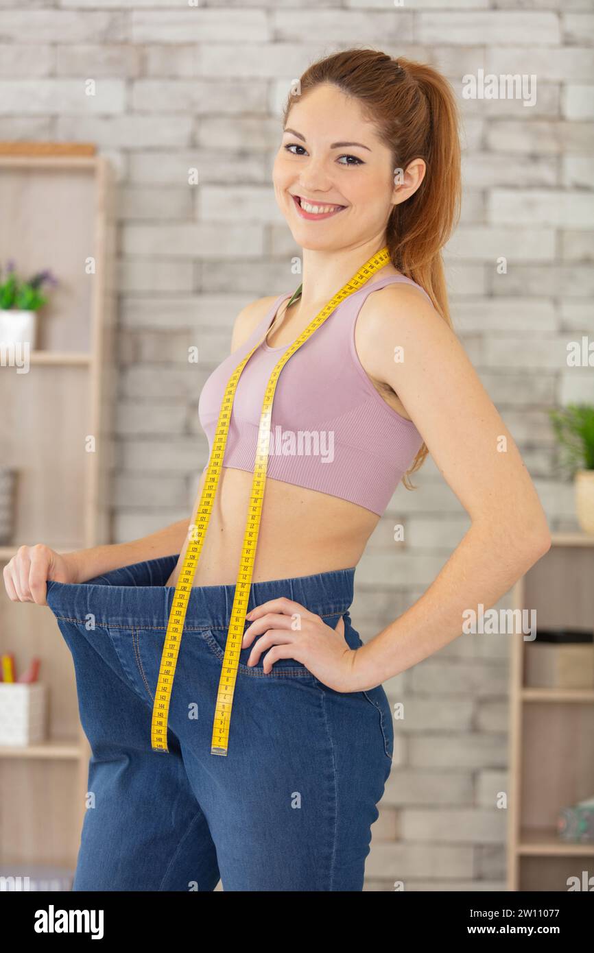 donna che tiene pantaloni grandi e metro dopo la dieta Foto Stock