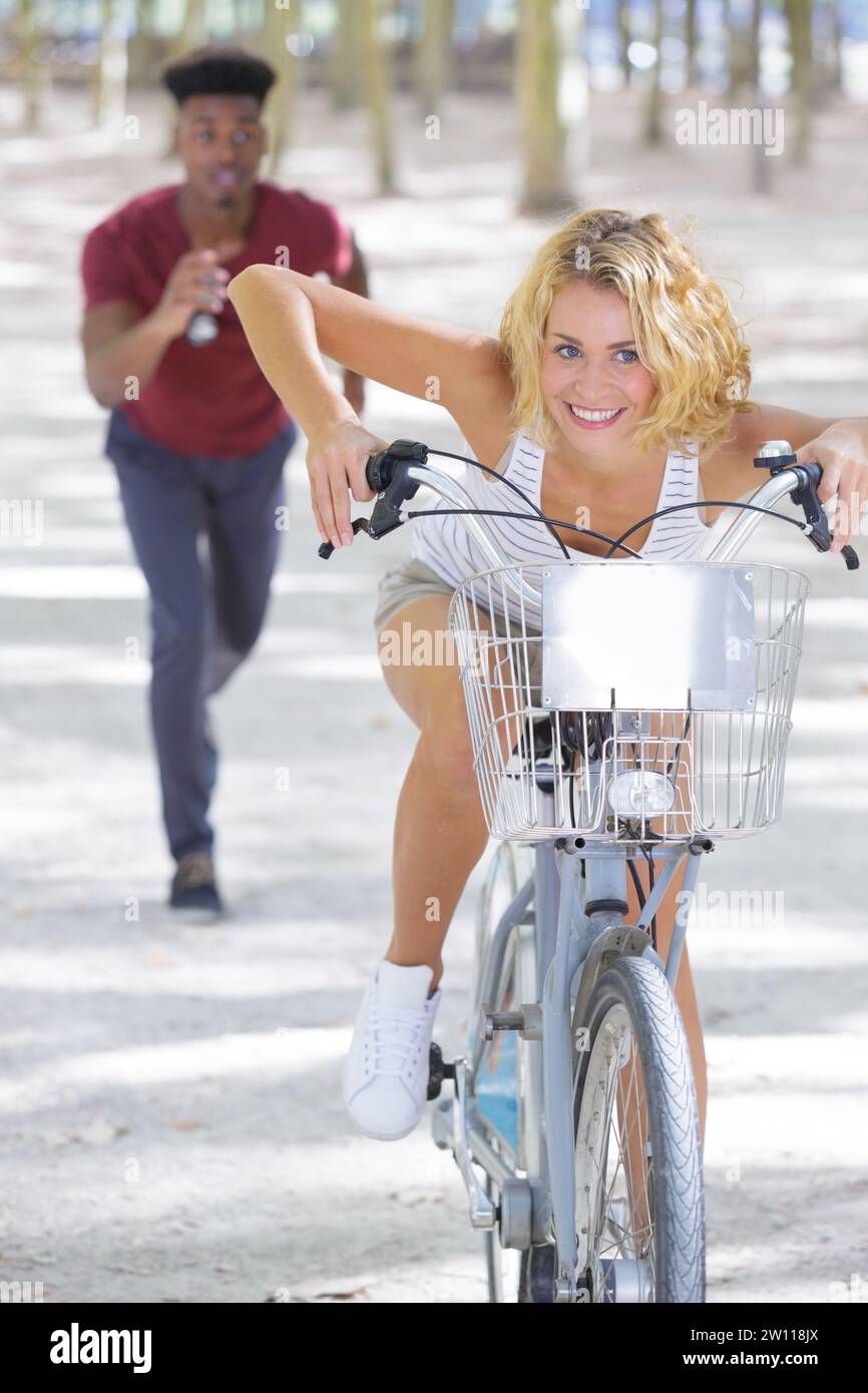 il ragazzo corre dietro la donna in bicicletta Foto Stock