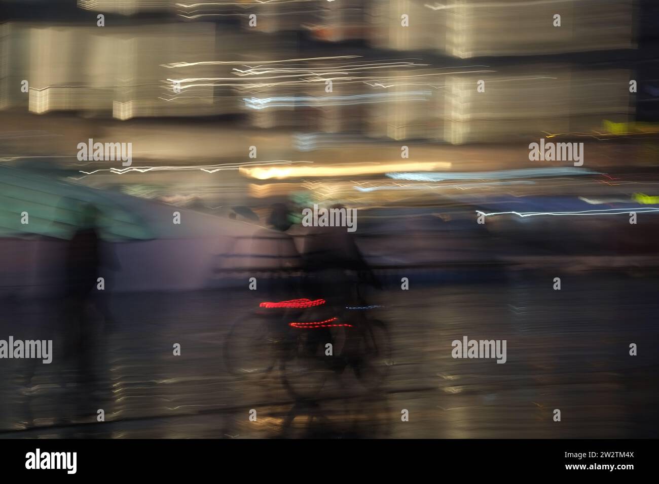Lunga esposizione di ciclisti e pedastriani irriconoscibili per strada di notte in un ambiente urbano Foto Stock
