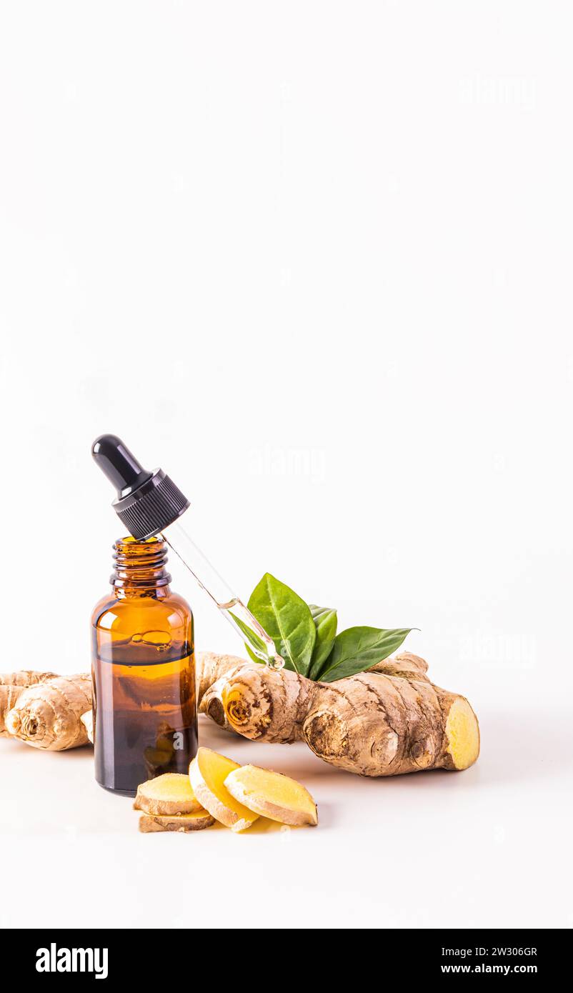 Una bottiglia cosmetica aperta con un prodotto per la cura dei capelli a base di olio di zenzero e un contagocce riempito con esso. tonico e antisettico. Vista verticale. sfondo bianco. Foto Stock