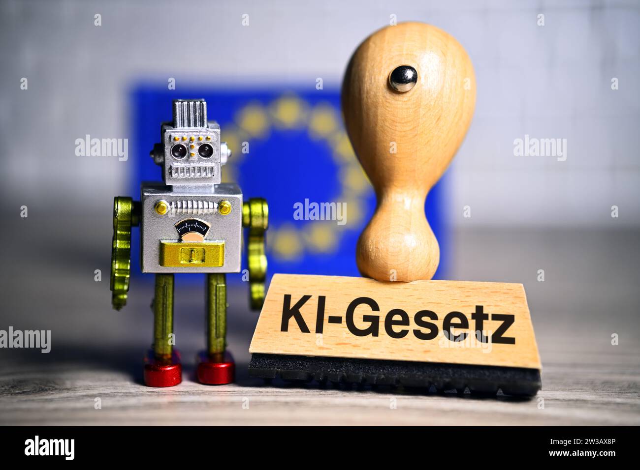FOTOMONTAGE, Miniaturroboter und Stempel mit Aufschrift KI-Gesetz vor einer europäischen Fahne Foto Stock