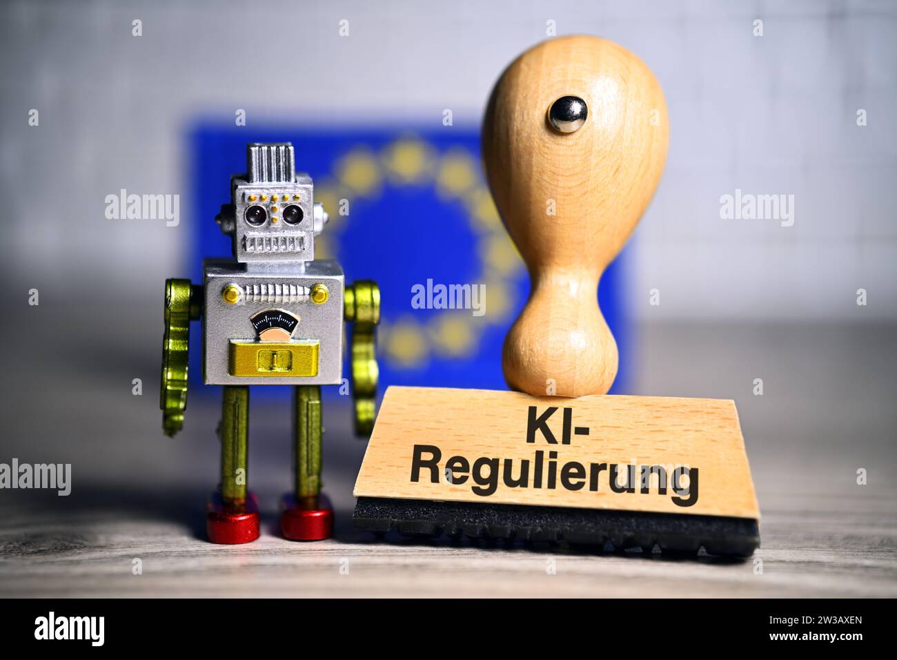 FOTOMONTAGE, Miniaturroboter und Stempel mit Aufschrift KI-Regulierung vor einer europäischen Fahne Foto Stock