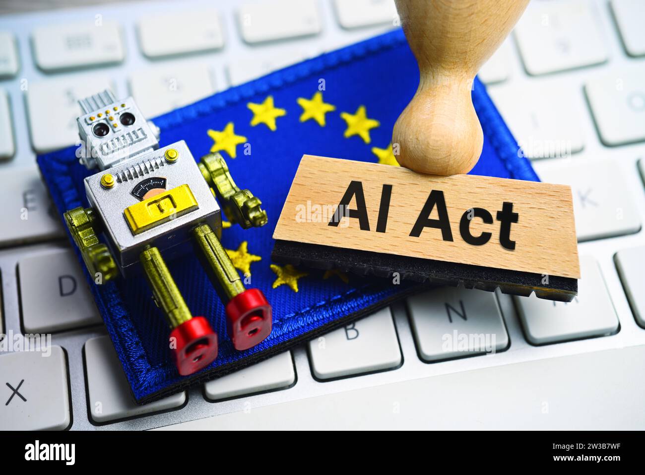 FOTOMONTAGE, Miniaturroboter und Stempel mit Aufschrift ai Act auf einer Computertastatur vor einer europäischen Fahne Foto Stock