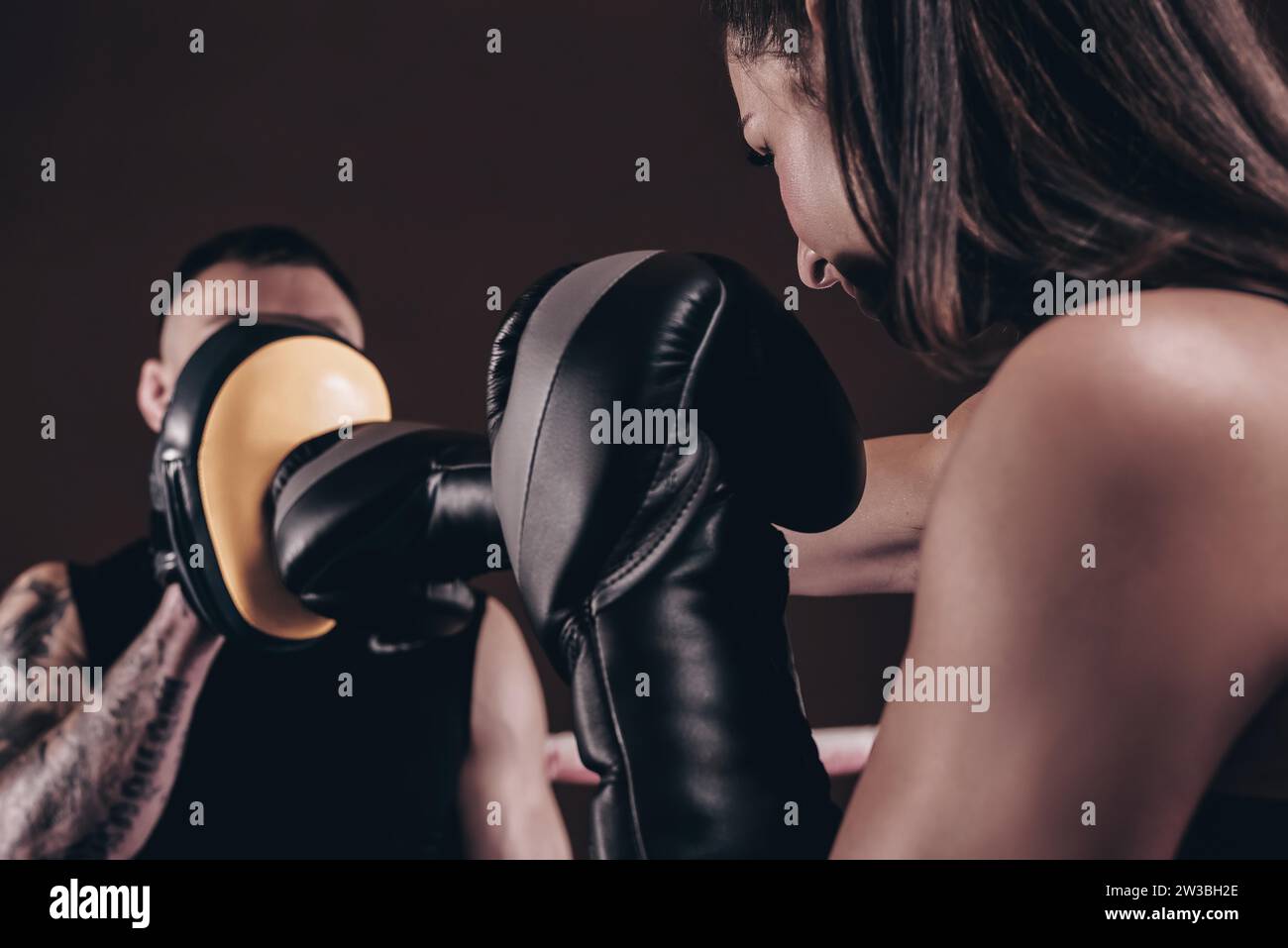Donna atletica in pantaloncini rossi e top pugilato con un allenatore. Boxe e arti marziali miste. Supporti misti Foto Stock