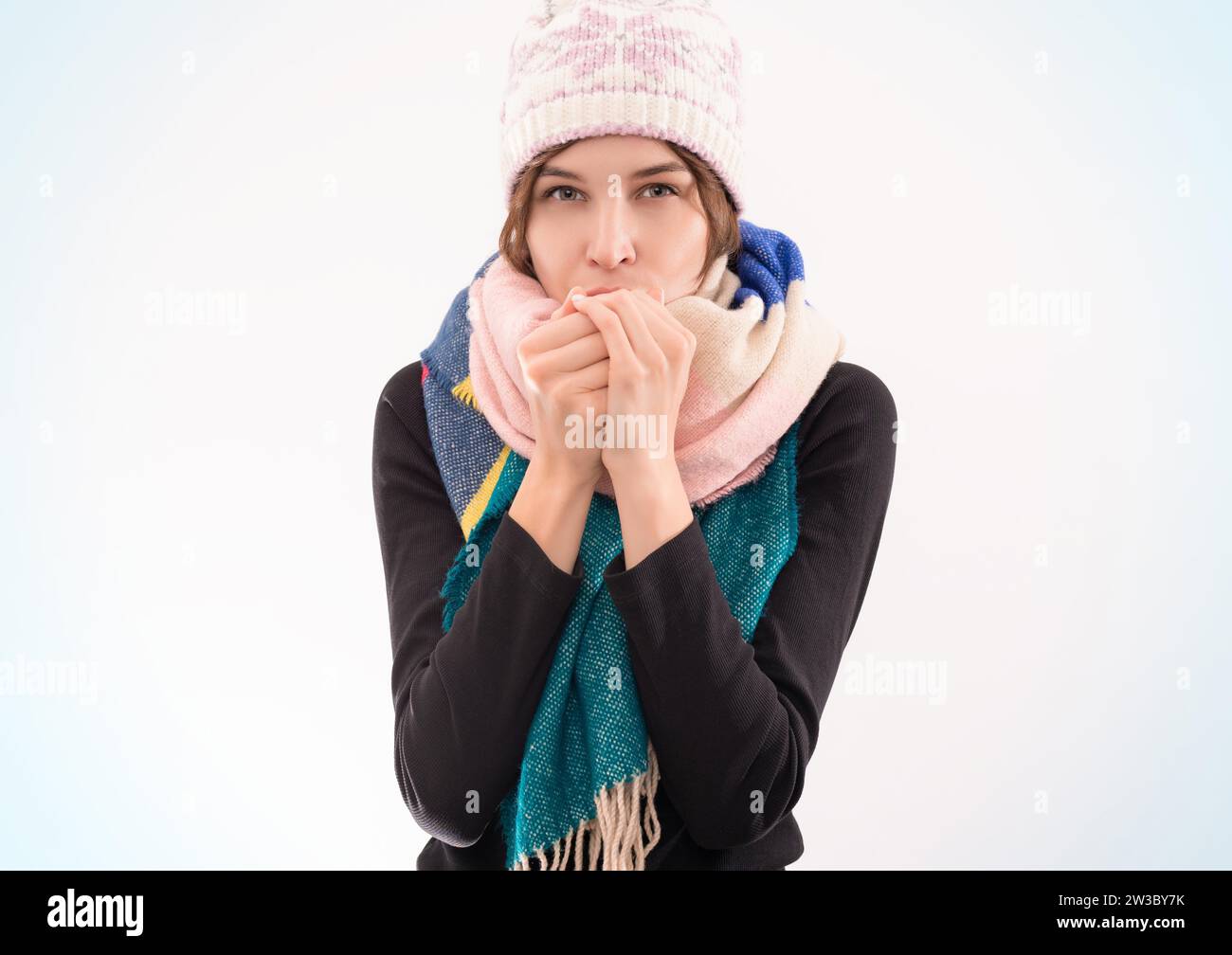 Ritratto di una donna con cappello e sciarpa invernali. Si scalda le mani con il respiro. Concetto di malattie virali. Supporti misti Foto Stock