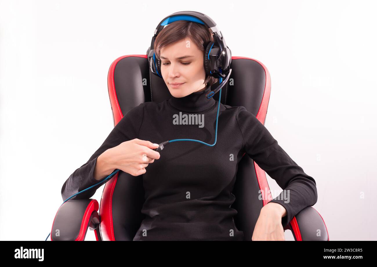 Ritratto di una donna seduta su una sedia da gioco rossa che indossa delle cuffie. Il concetto di simulatori di gioco e di e-sport. Supporti misti Foto Stock