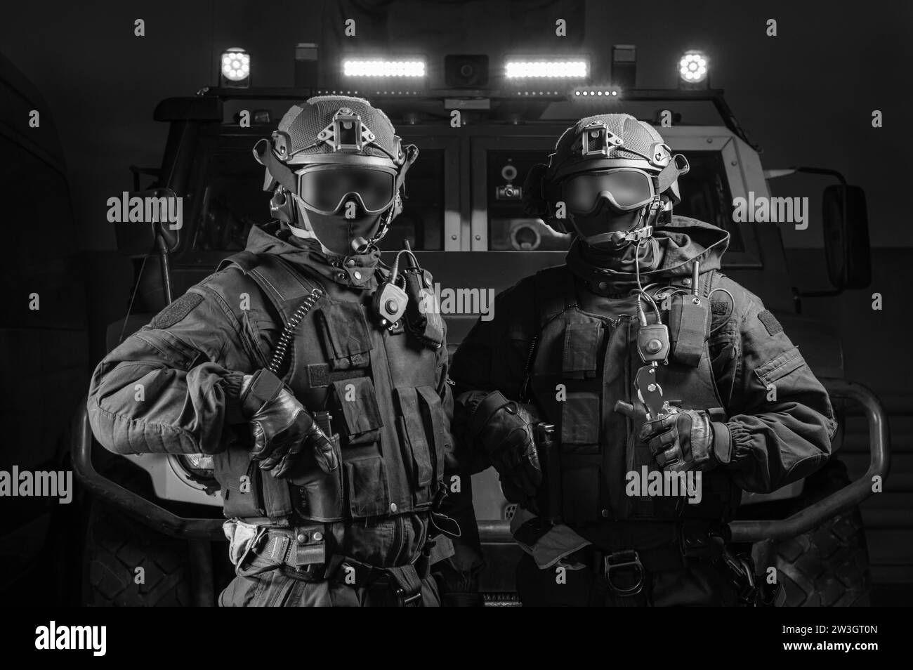 Due uomini in uniforme militare stanno in un hangar con un camion sullo sfondo. Concetto SWAT. Supporti misti Foto Stock