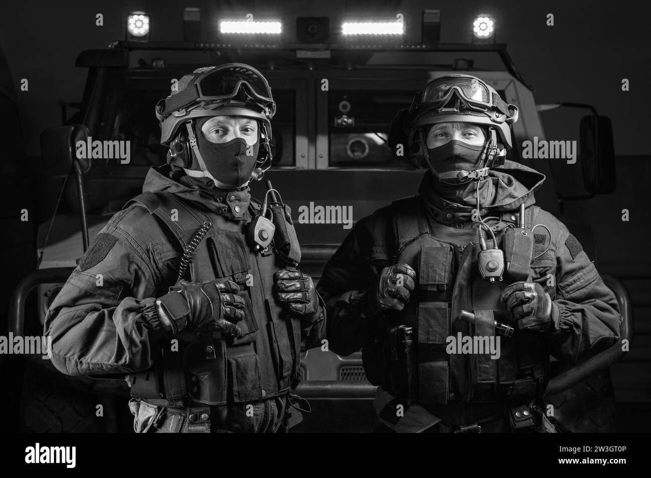 Due uomini in uniforme militare stanno in un hangar con un camion sullo sfondo. Concetto SWAT. Supporti misti Foto Stock