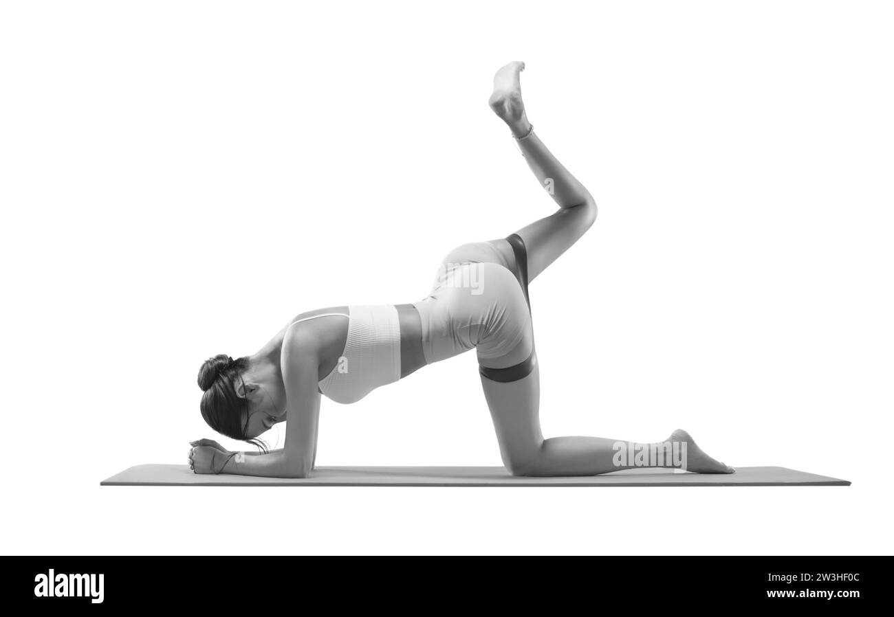 Donna affascinante che fa esercizio fisico per tirare la coscia con una fascia elastica. Isolato su bianco. Il concetto di sport, fitness, pilates Foto Stock