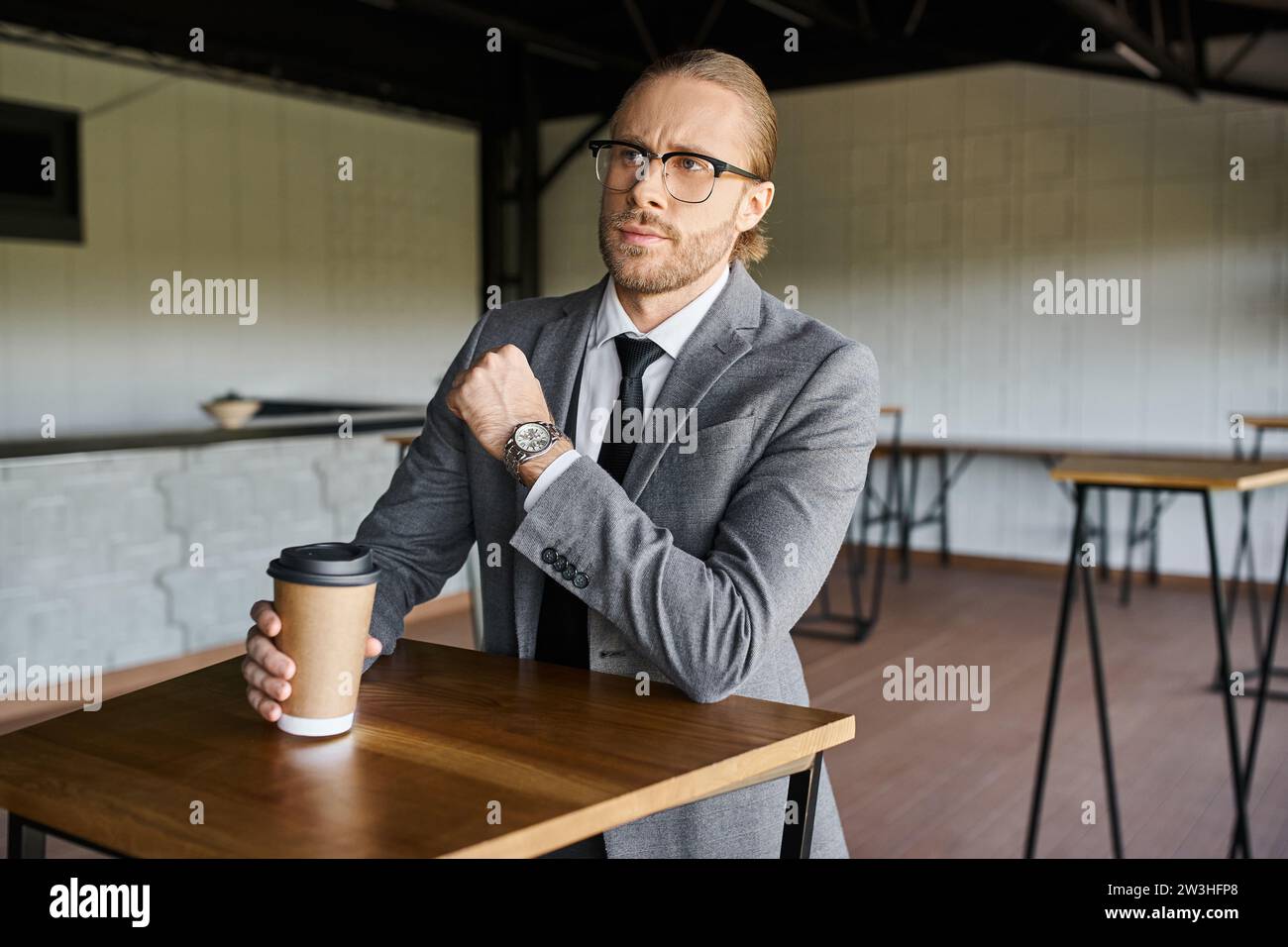 elegante e professionale in un'elegante tuta che regge una tazza di caffè e guarda lontano, concetto di business Foto Stock