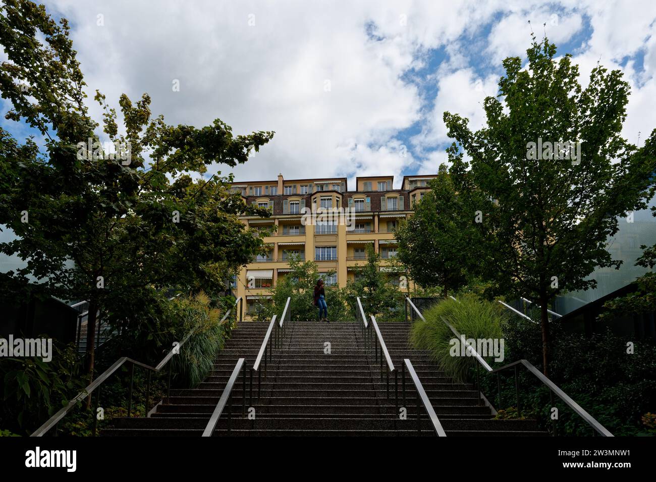 Scendi scendi scale emergono dal Leman Express alla stazione di Champel, Ginevra, incorniciato da ombre degli alberi, con una figura solitaria sagomata in cima. Foto Stock